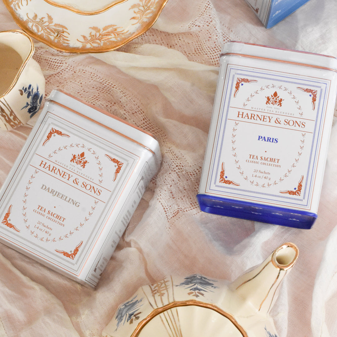 Harney & Sons tea packages on a decorative tablecloth with teacups and a teapot.